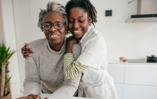 A professional caregiver embraces an elderly woman in a bright home setting, highlighting compassionate senior care, emotional support, and meaningful companionship that enhances quality of life through in-home care services.